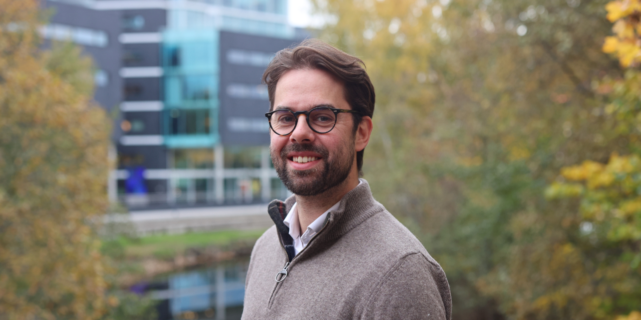 Homme &agrave; lunettes souriant devant un immeuble de bureaux