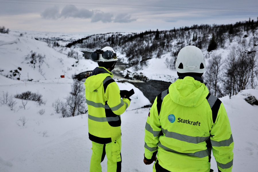 Deux collègues portant des équipements de sécurité au sommet d'une colline au-dessus du barrage de Nesjø